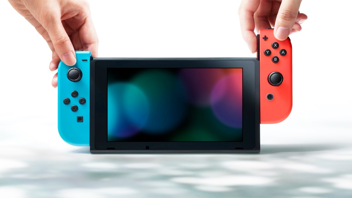 Eine Nintendo Switch mit rotem und blauen Joy-Con sowie zwei Händen.